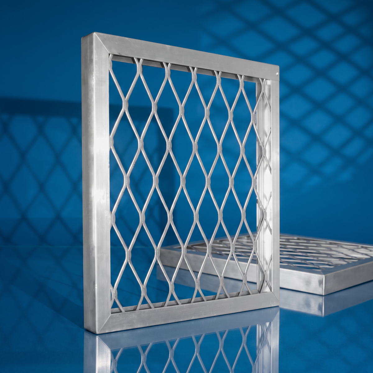 One inch aluminum air filter frame with diamond wire grid, shown upright and flat on a blue backdrop
