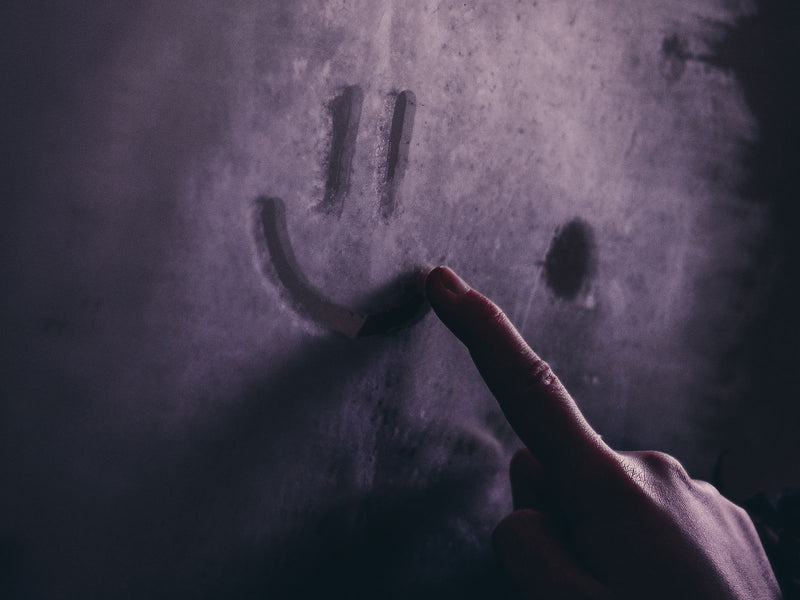 A finger drawn through a thick layer of household dust on a dark surface