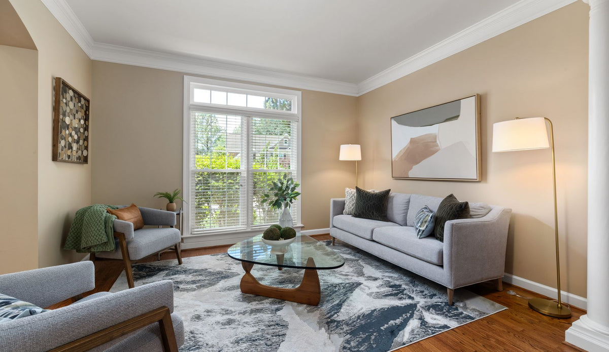 Bright, sunlit living room in a family home with sofa, armchairs and a large window