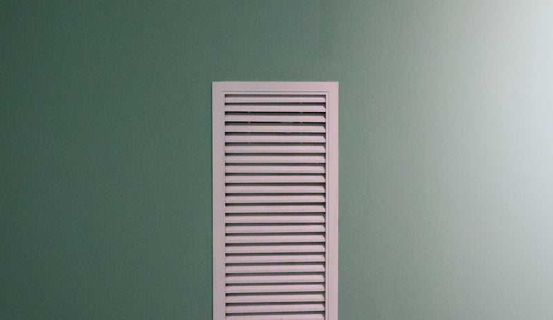 White return air vent set into a soft green wall
